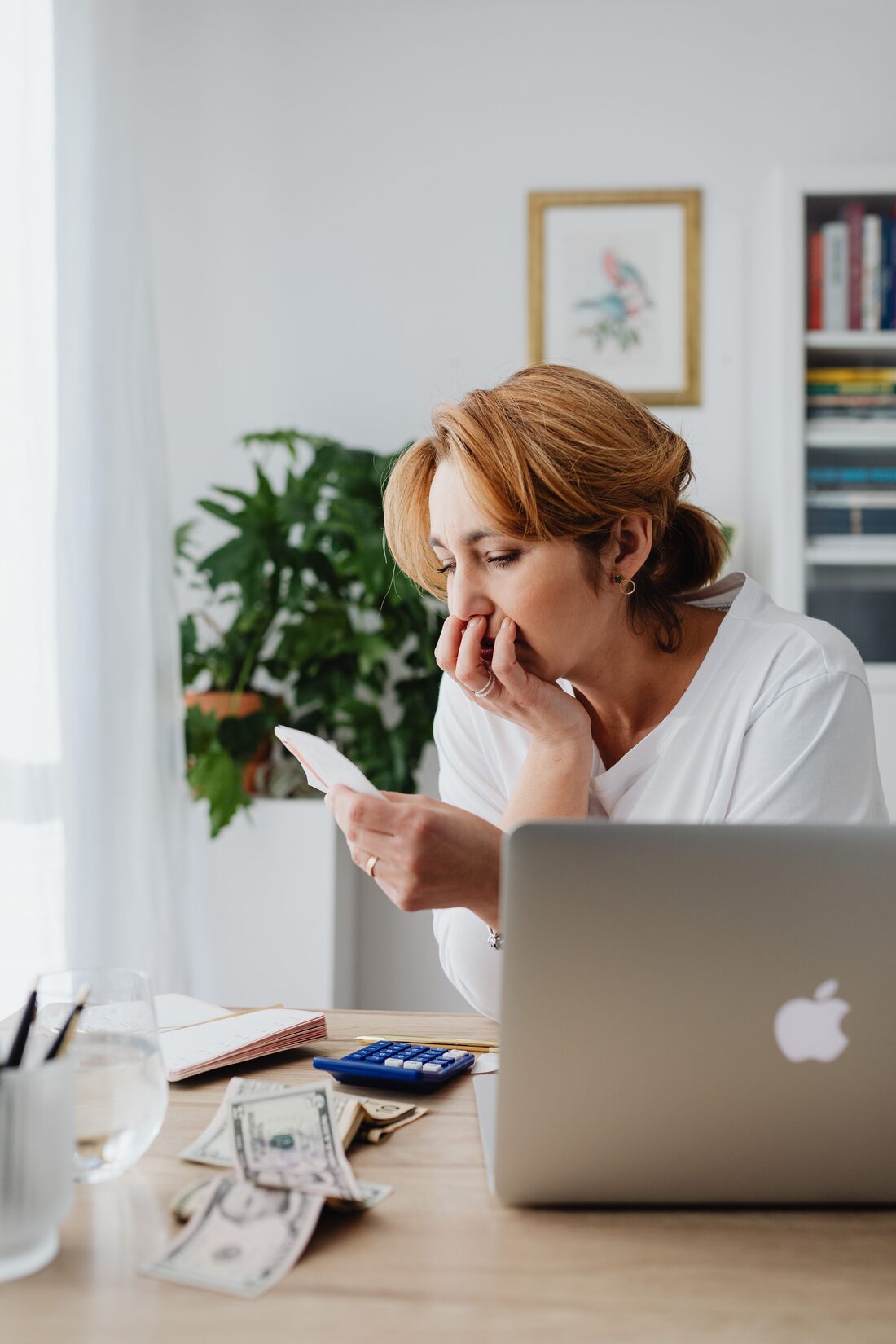 A caregiver at home, worn down while managing bills and messages